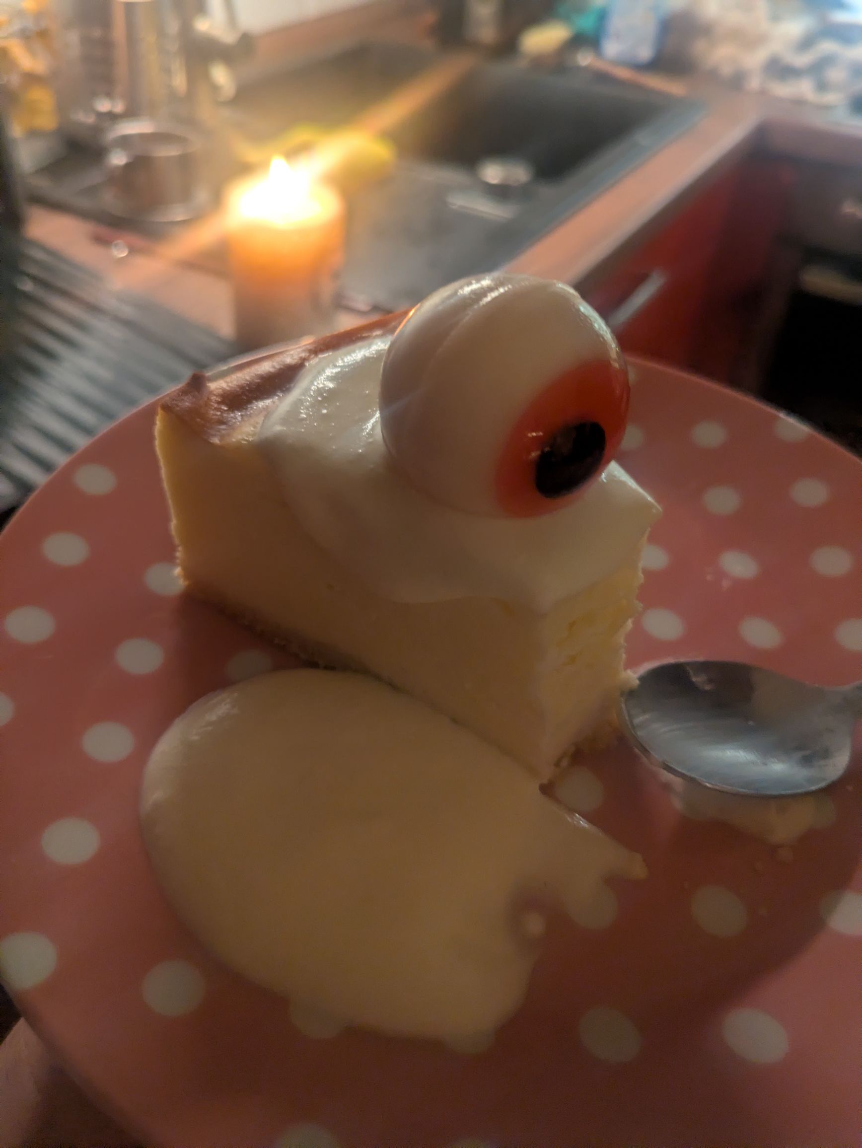 A cheescake, with cream and an eyeball sweet on top of it